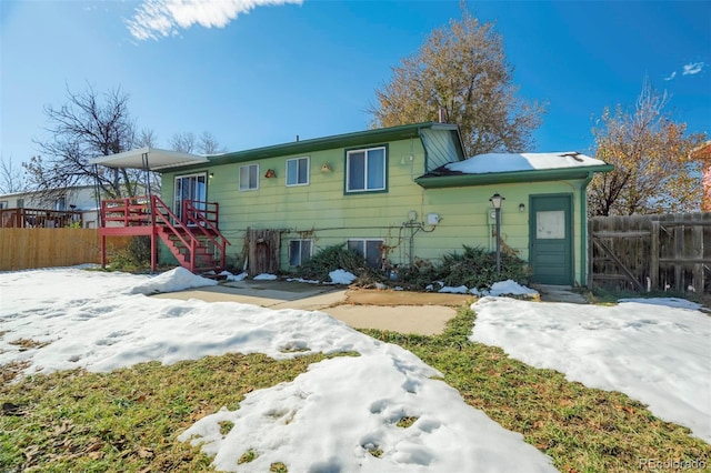 snow covered back of property with a wooden deck