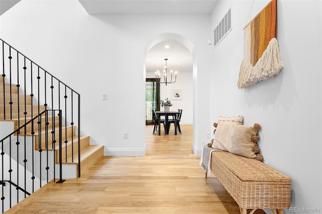 659 Albion St, Denver, CO 80220 - hallway with arched walkways, wood finished floors, a chandelier, stairs, and baseboards