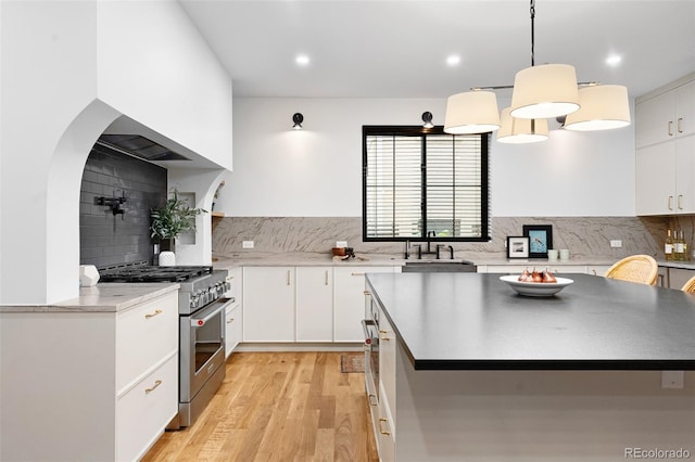 659 Albion St, Denver, CO 80220 - kitchen featuring stainless steel stove, tasteful backsplash, light wood-type flooring, a sink, and white cabinets
