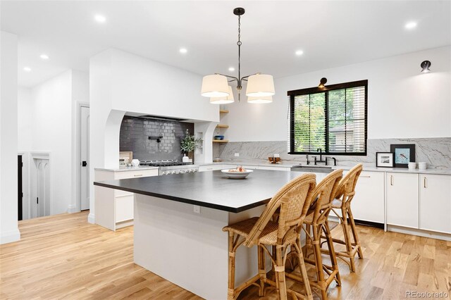 659 Albion St, Denver, CO 80220 - kitchen featuring tasteful backsplash, light wood finished floors, a kitchen island, recessed lighting, and white cabinetry