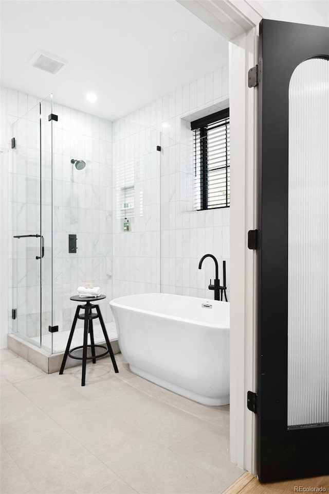 659 Albion St, Denver, CO 80220 - bathroom with a freestanding bath, tile walls, a shower stall, and tile patterned flooring