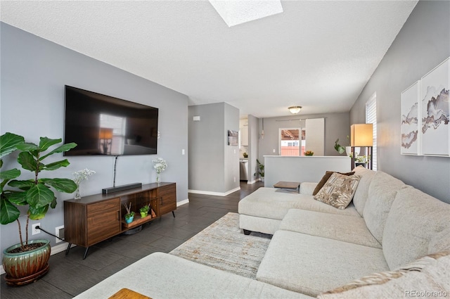 living area featuring a skylight, a textured ceiling, baseboards, and wood finished floors