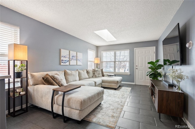 living area with a skylight, baseboards, and a textured ceiling