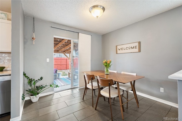 dining room with a textured ceiling and baseboards