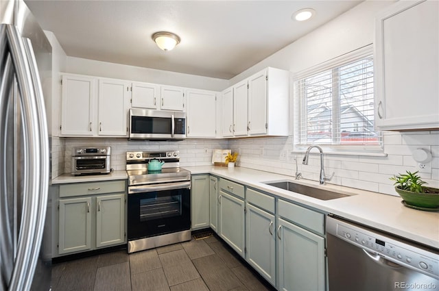 kitchen featuring stainless steel appliances, tasteful backsplash, a sink, and light countertops