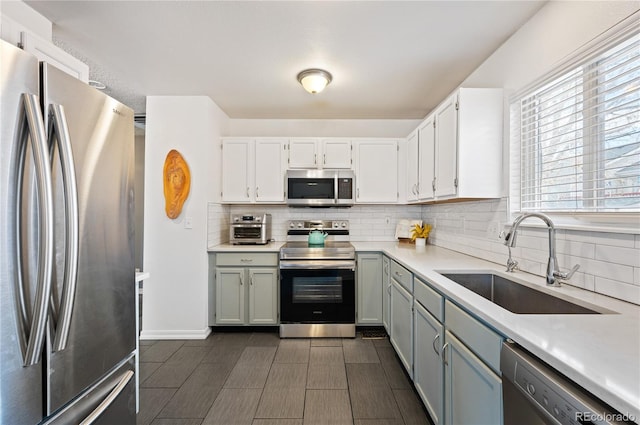 kitchen with stainless steel appliances, tasteful backsplash, a sink, and light countertops