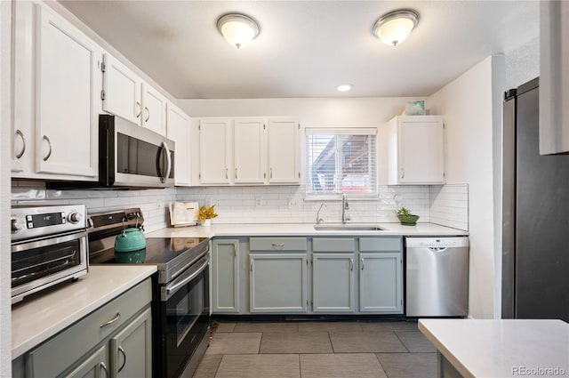 kitchen featuring appliances with stainless steel finishes, light countertops, a sink, and decorative backsplash