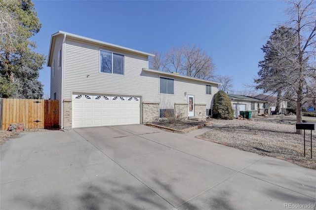 view of front facade featuring a garage, concrete driveway, brick siding, and fence