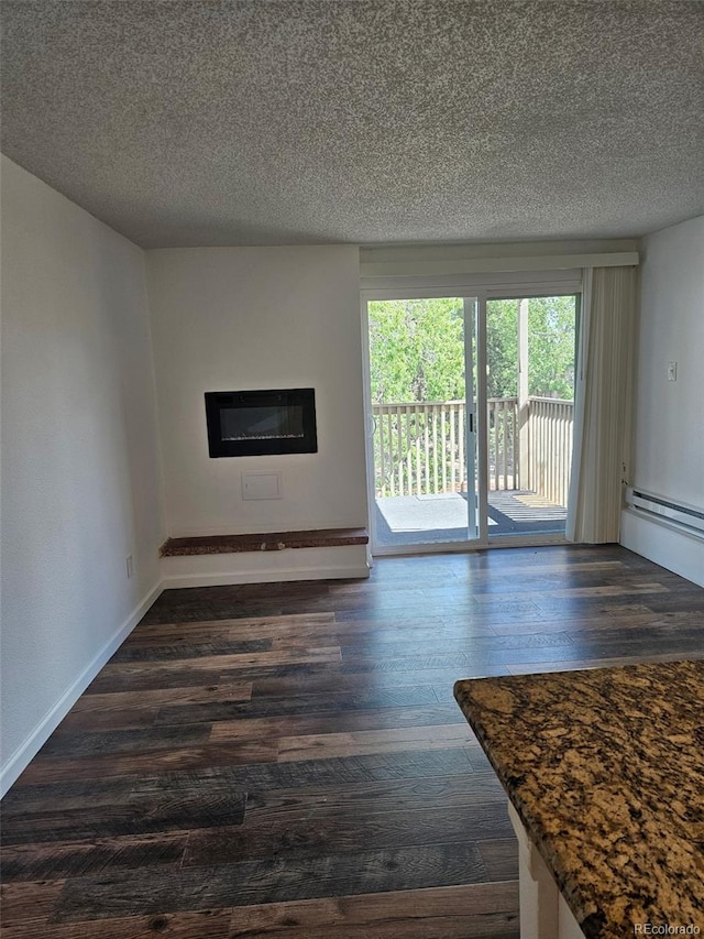 1304 S Parker Rd Unit 13, Denver, CO 80231 - unfurnished living room featuring dark wood-type flooring, a textured ceiling, a glass covered fireplace, and baseboards