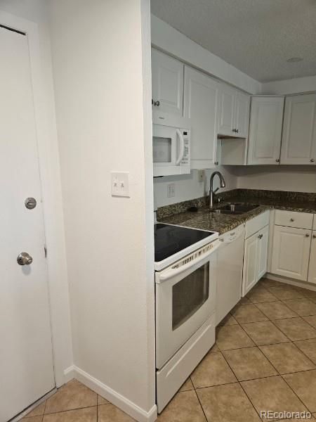 1304 S Parker Rd Unit 13, Denver, CO 80231 - kitchen with white appliances, a sink, light tile patterned floors, white cabinets, and baseboards