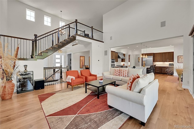 6639 S Vandriver Way, Aurora, CO 80016 - living area featuring light wood-type flooring, a towering ceiling, and stairway