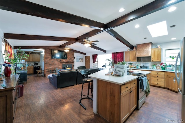 kitchen with ceiling fan, a center island, dark wood-type flooring, vaulted ceiling with skylight, and custom range hood