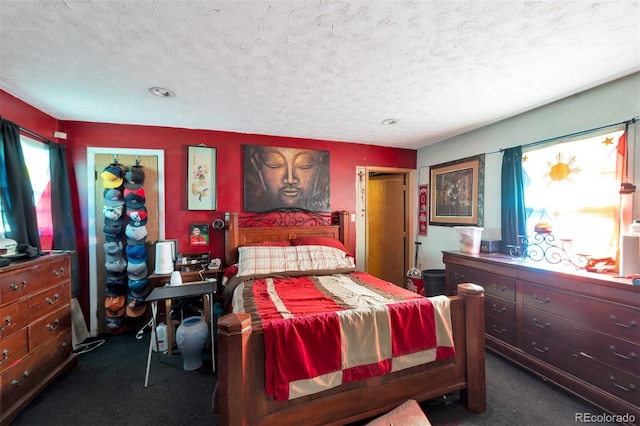 bedroom with a textured ceiling and dark carpet