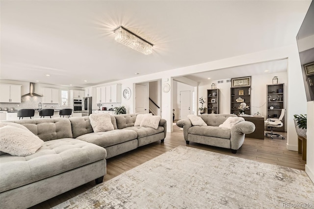 living room featuring a chandelier, light hardwood / wood-style flooring, and sink