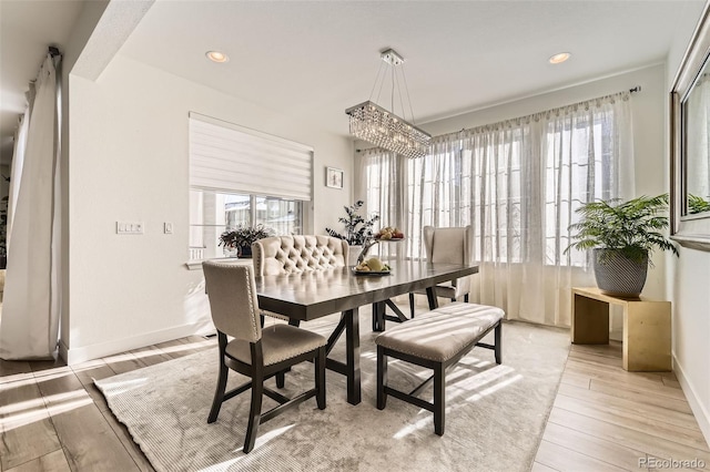 dining space with light wood-type flooring and a notable chandelier