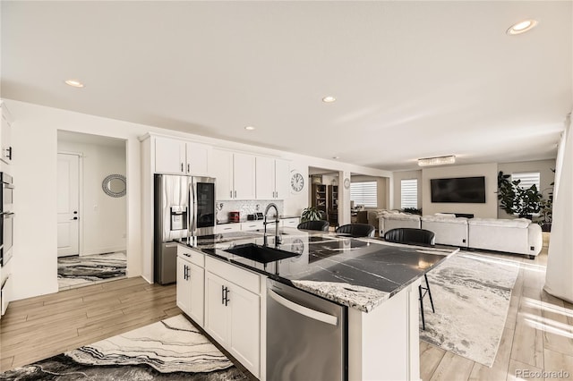 kitchen featuring white cabinets, sink, an island with sink, and appliances with stainless steel finishes