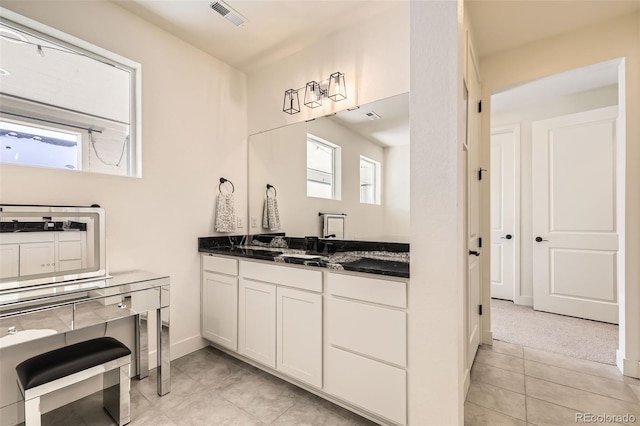 kitchen with plenty of natural light, white cabinetry, light carpet, and dark stone counters