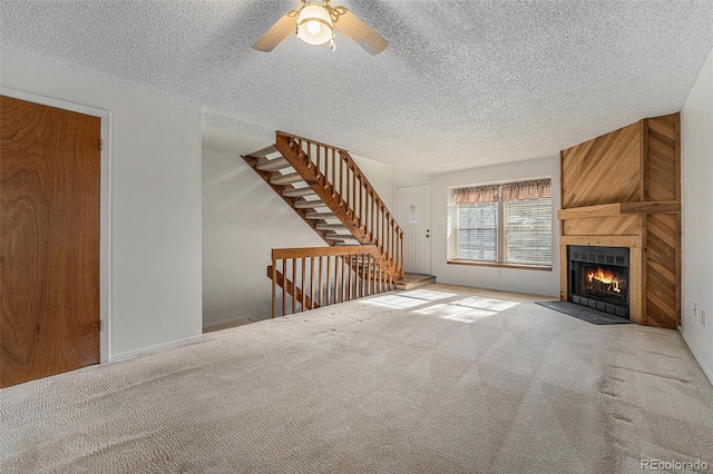 unfurnished living room featuring a large fireplace, carpet, and a textured ceiling