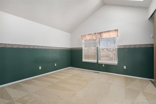 carpeted empty room with a textured ceiling and lofted ceiling