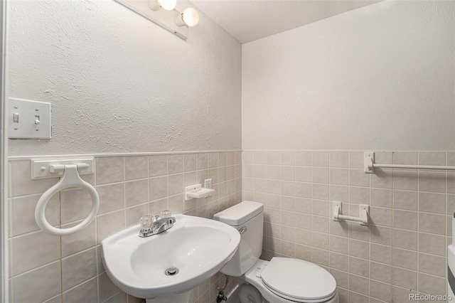 bathroom featuring sink, toilet, and tile walls