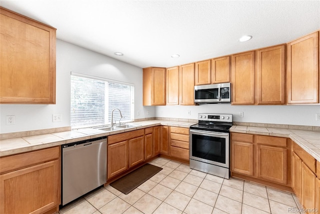 13180 Jasmine St, Thornton, CO 80602 - kitchen with stainless steel appliances, a sink, light tile patterned floors, tile counters, and recessed lighting