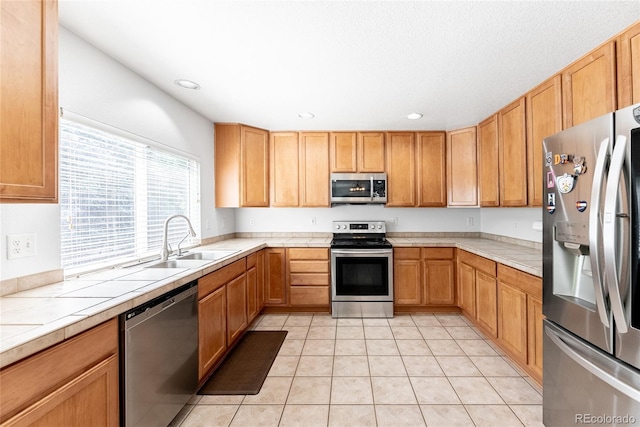 13180 Jasmine St, Thornton, CO 80602 - kitchen featuring appliances with stainless steel finishes, a sink, tile countertops, light tile patterned floors, and recessed lighting
