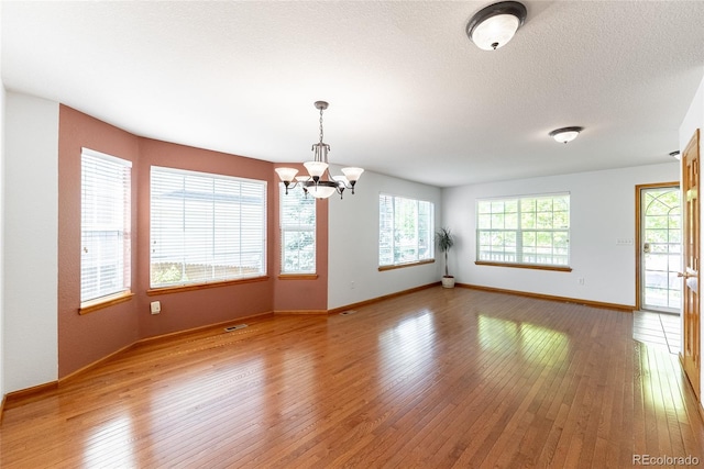 13180 Jasmine St, Thornton, CO 80602 - unfurnished room featuring a chandelier, plenty of natural light, light wood-style flooring, and baseboards