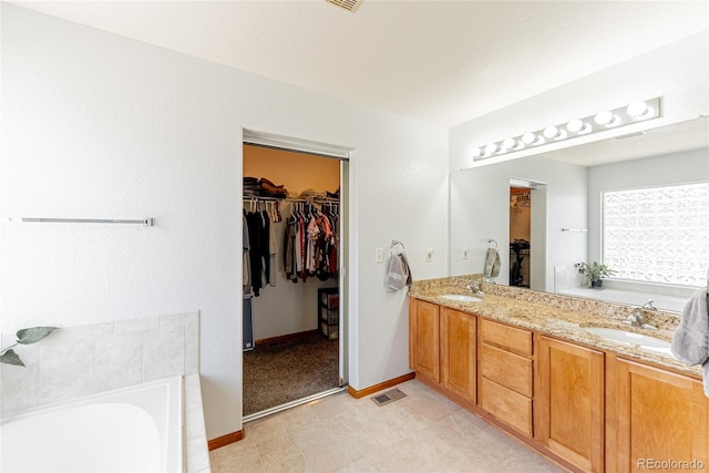 13180 Jasmine St, Thornton, CO 80602 - bathroom featuring a garden tub, double vanity, a walk in closet, and baseboards