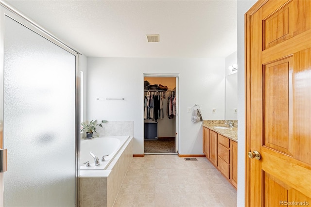 13180 Jasmine St, Thornton, CO 80602 - bathroom featuring a bath, vanity, a stall shower, a walk in closet, and baseboards