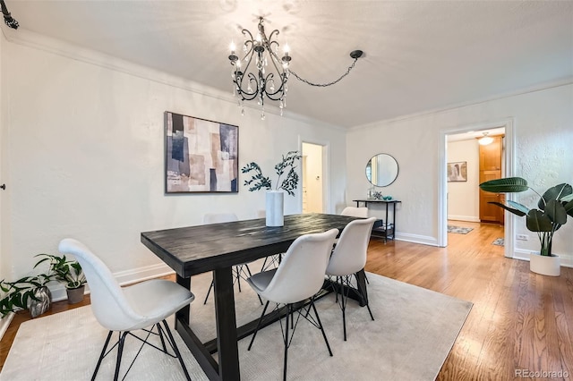 dining space with crown molding, light wood-style floors, baseboards, and a chandelier