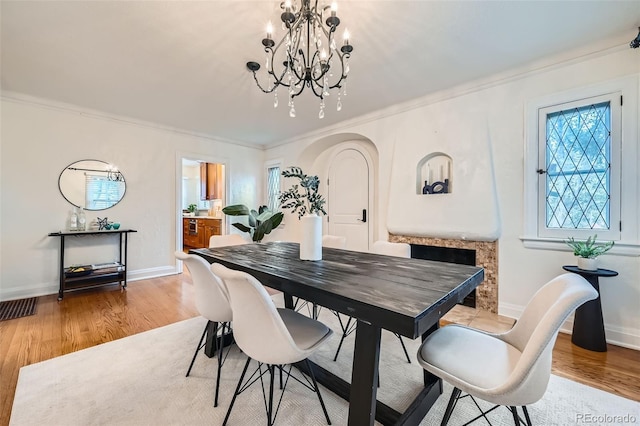 dining area with visible vents, light wood-style floors, crown molding, and a notable chandelier