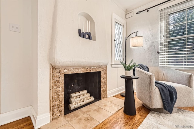 living area featuring baseboards, wood finished floors, and a tile fireplace