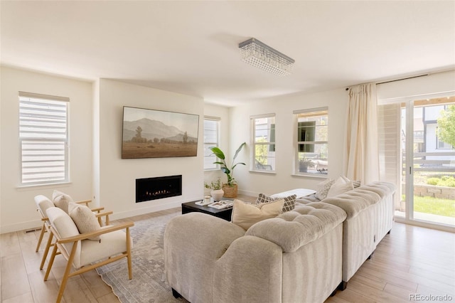 6506 Barnstead Dr, Castle Pines, CO 80108 - living area featuring light wood-style floors, a lit fireplace, and baseboards