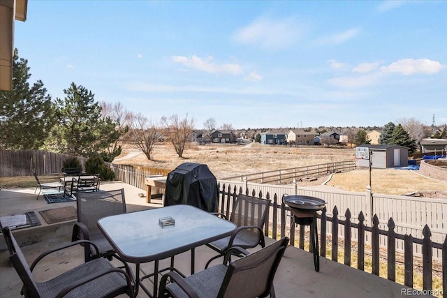 view of patio featuring a storage unit, a fenced backyard, an outbuilding, and outdoor dining space