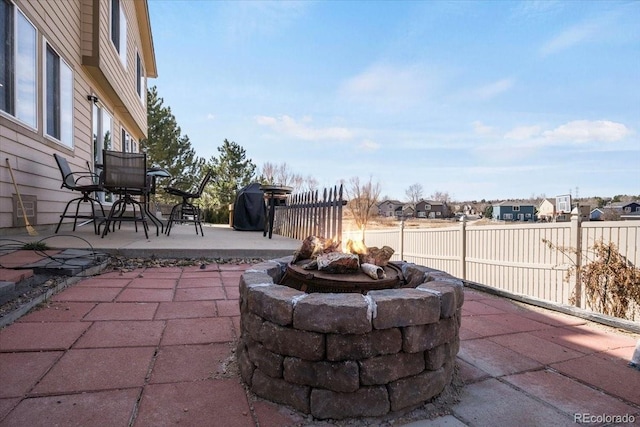 view of patio featuring fence, a residential view, and a fire pit