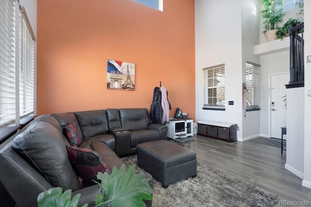 living room with a high ceiling, baseboards, and wood finished floors