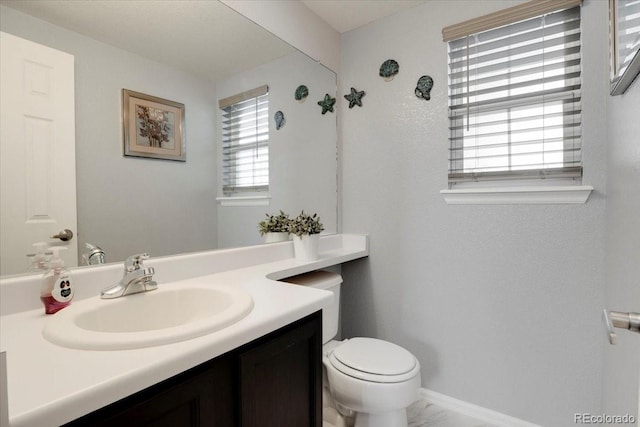 bathroom with baseboards, toilet, and vanity