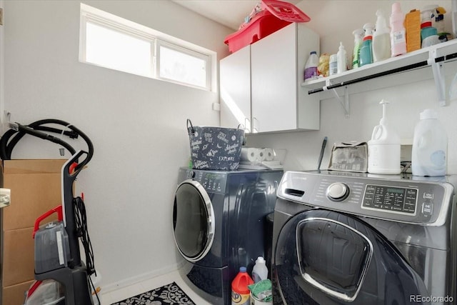 laundry room featuring washing machine and dryer, cabinet space, and baseboards