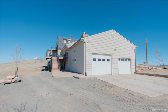 view of property exterior featuring stairway, driveway, and a chimney