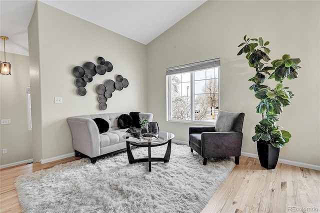 living room with lofted ceiling, wood finished floors, and baseboards