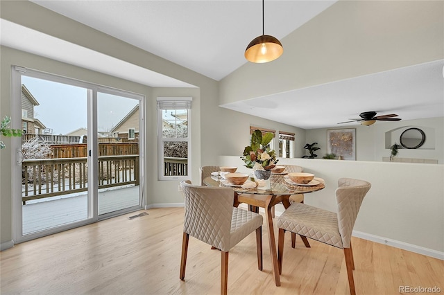 dining space with lofted ceiling, baseboards, visible vents, and light wood-style floors