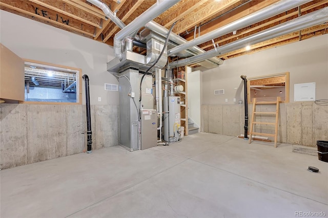 basement featuring water heater, visible vents, and heating unit