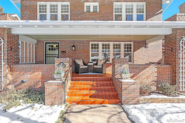 snow covered property entrance with covered porch