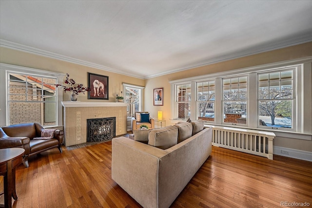 living room featuring radiator heating unit, ornamental molding, a tile fireplace, and a healthy amount of sunlight