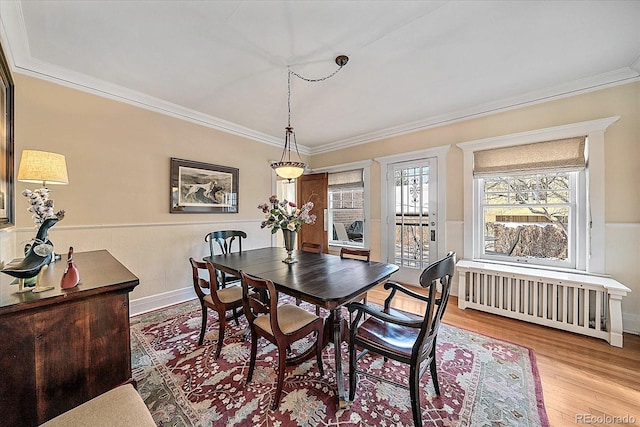 dining space featuring ornamental molding, radiator, and light hardwood / wood-style flooring