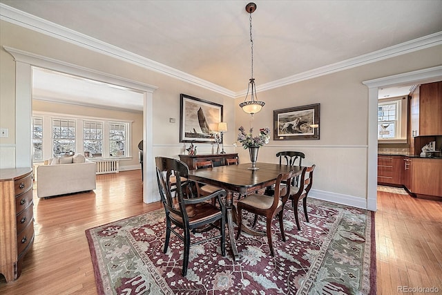 dining space with ornamental molding, a healthy amount of sunlight, and light wood-type flooring