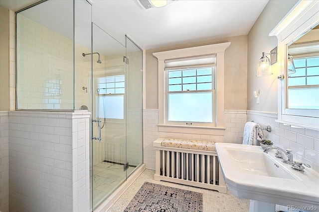 bathroom with tile patterned flooring, sink, tile walls, and a shower with shower door