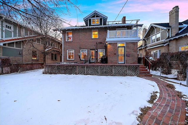 snow covered back of property with a balcony