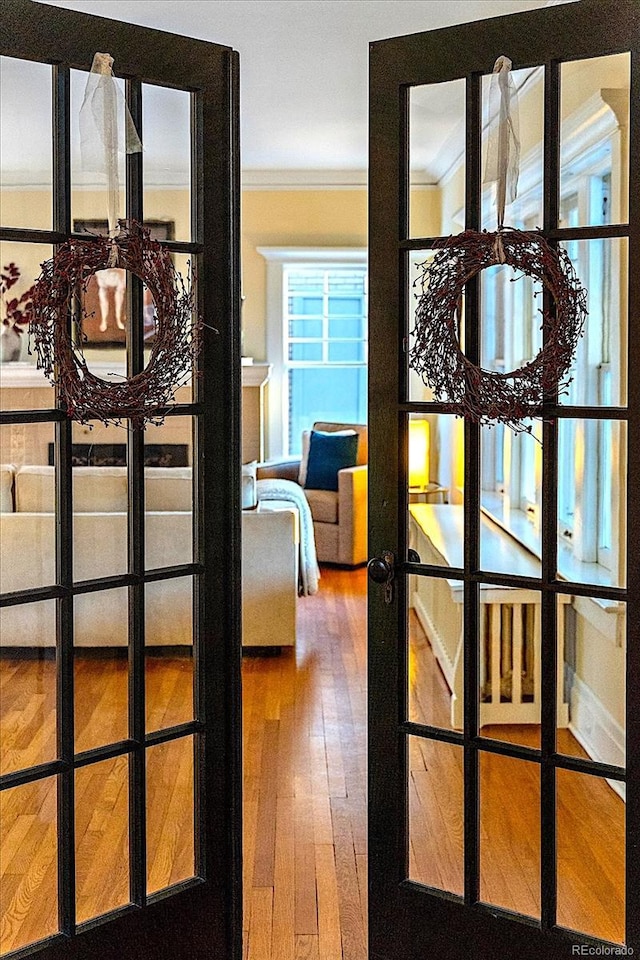 doorway with ornamental molding, hardwood / wood-style floors, and french doors