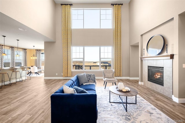 living room featuring a fireplace, hardwood / wood-style floors, a towering ceiling, and a notable chandelier